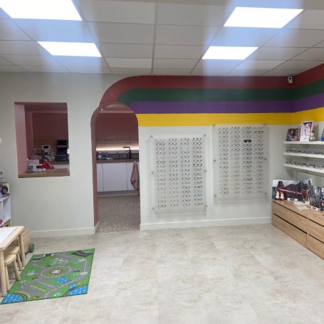 Intérieur d'une boutique avec un sol clair, des rayonnages et des murs colorés.