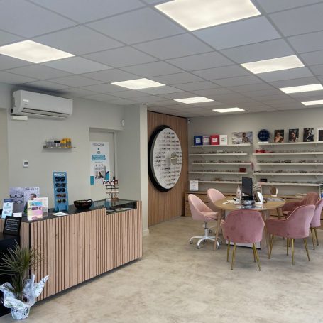 Intérieur d'un bureau moderne avec un comptoir d'accueil et des tables rondes.